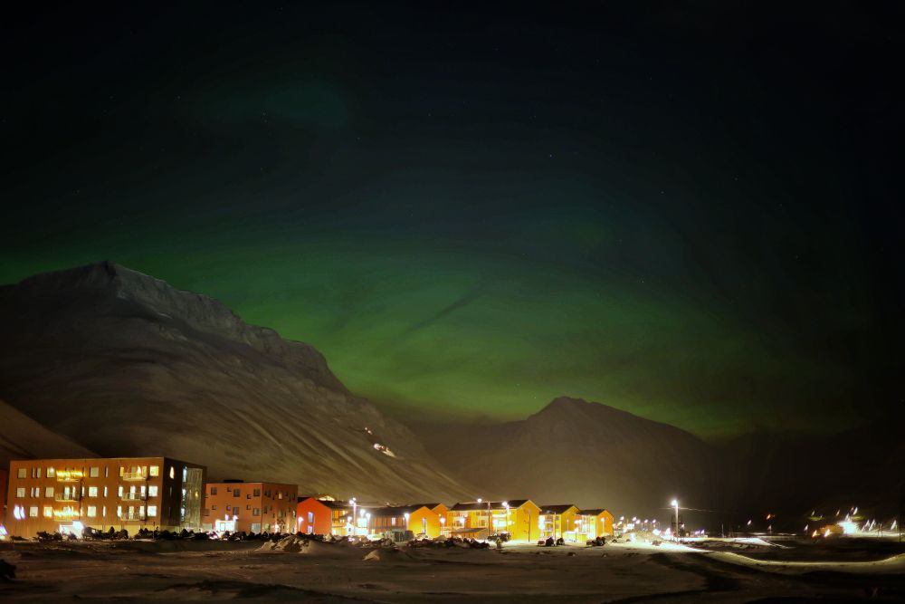 Mountains and a small town against a cloudy green sky 