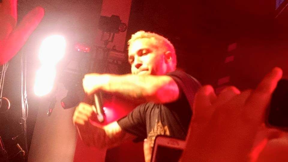 Pete Wentz, bassist of American rock band Fall Out Boy is shown arms out in front of himself as he is being lifted off a stage and carried into a crowd of fans.