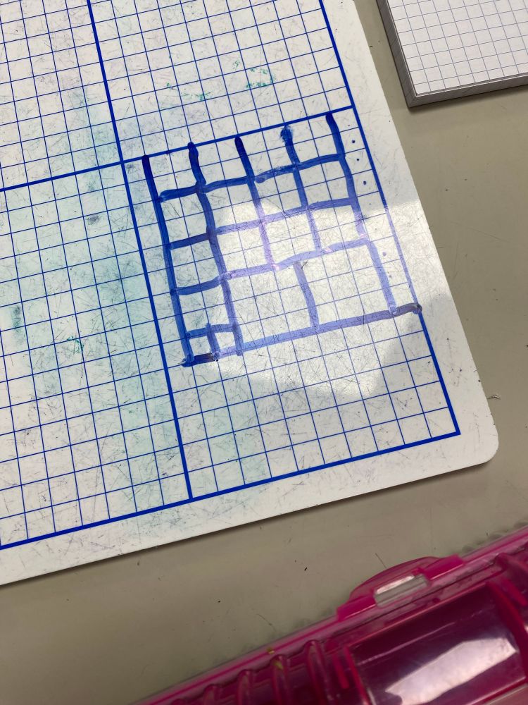 Photo shows a students work on a mini whiteboard.  A 9 by 9  square is drawn and students is dividing it into smaller squares.  