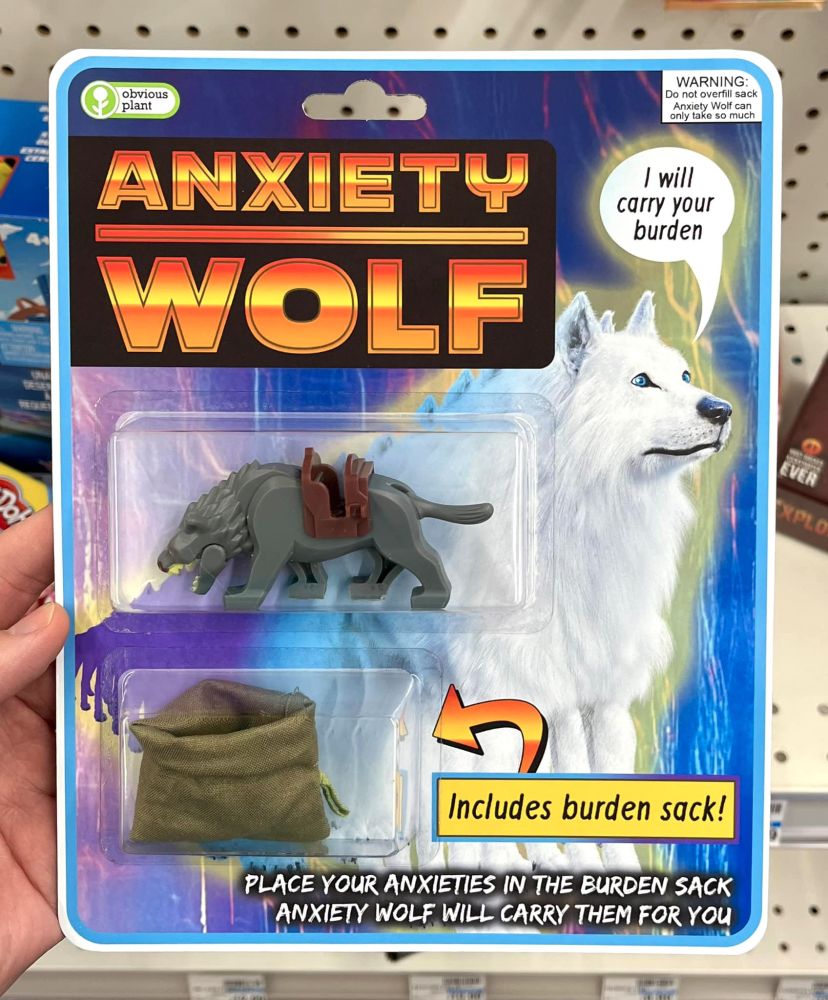 Realistic mock-up of a bubble-carded toy. The sections contain a draw string sack and a plastic toy wolf.

Text: ANXIETY WOLF

Includes burden sack!

Place your anxieties in the burden sack
Anxiety wolf will carry them for you

Advisory in the corner: WARNING Do not overfil sack Anxiety wolf can only take so much.