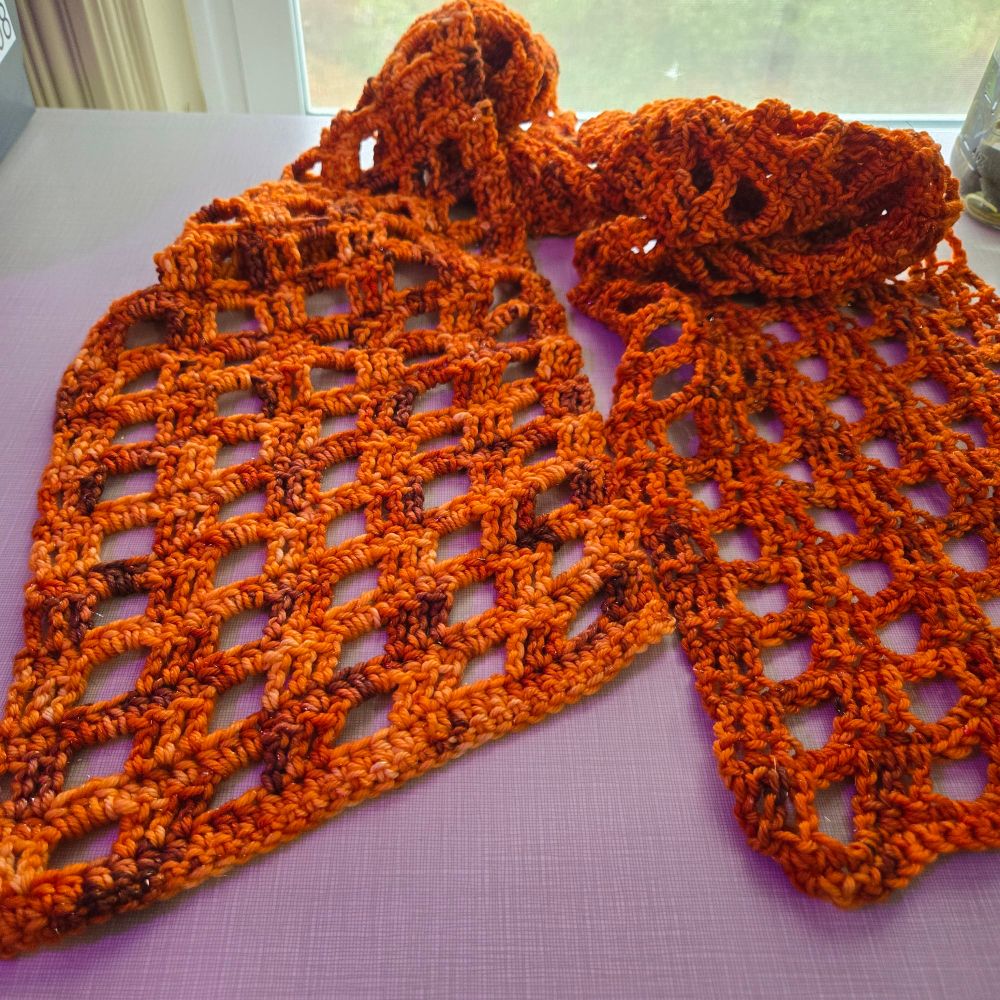 A crocheted orange scarf. It's a windowpane design made of chains, single crochet, and treble crochet stitches