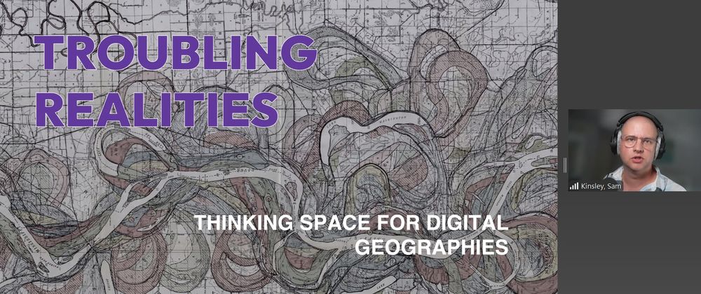 Zoom screenshot: to the right is an image of Sam Kinsley wearing a white shirt, glasses, and headphones. The background is blurred. To the left is the title presentation slide: troubling realities: Thinking space for digital geographies