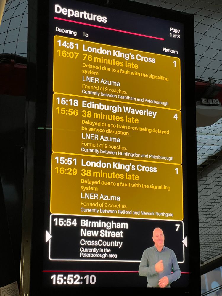 A train departures board showing various delayed train services. Someone is signing in the bottom right corner.   