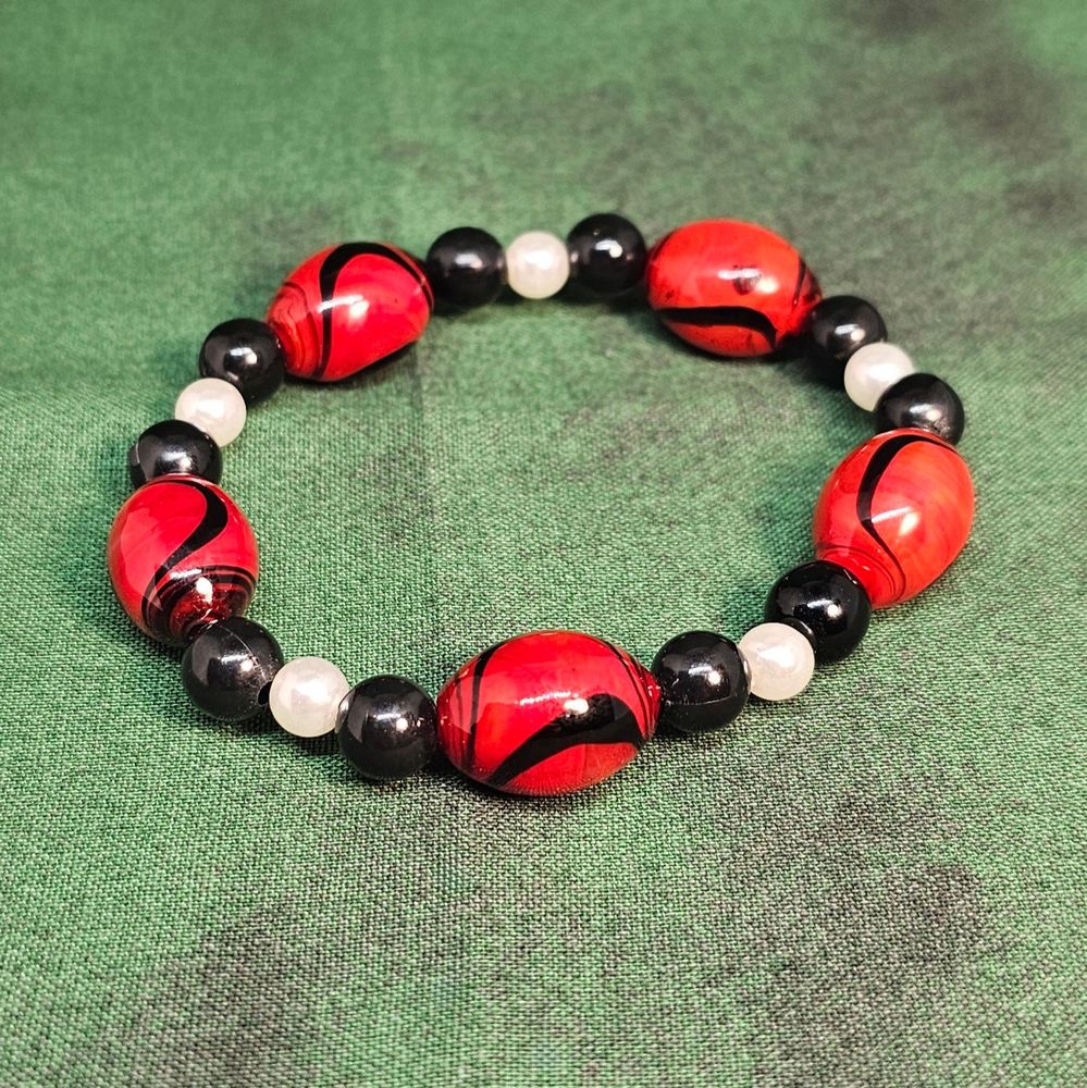 Red, black, and white beaded bracelet on a green background