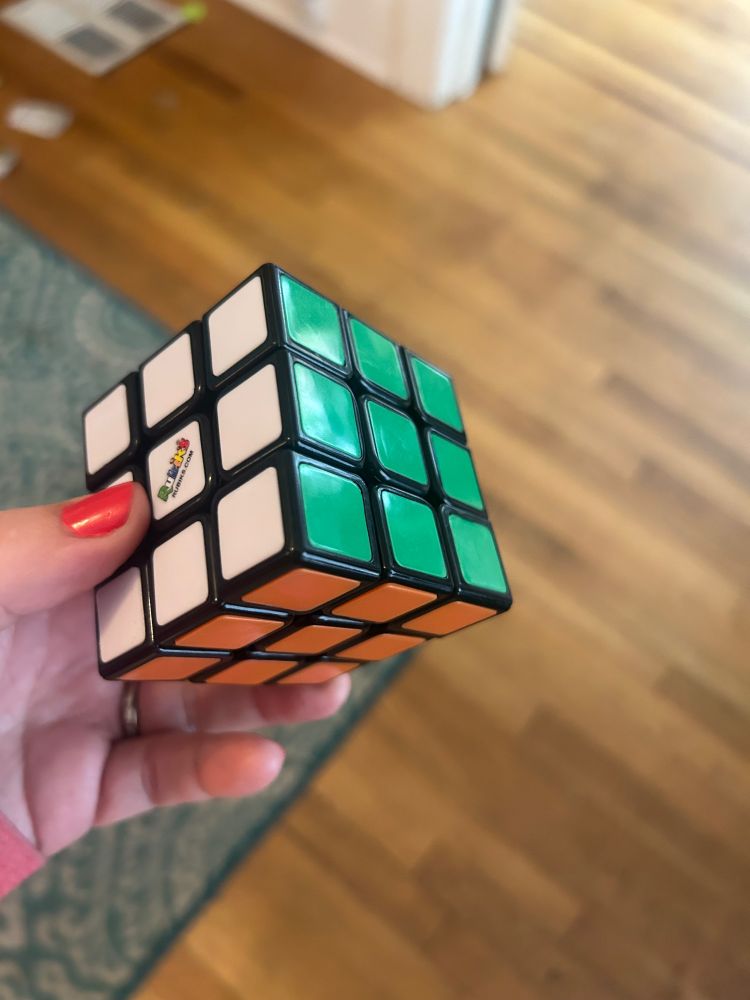 A solved Rubik’s Cube! Showing the white, green, and orange sides. 