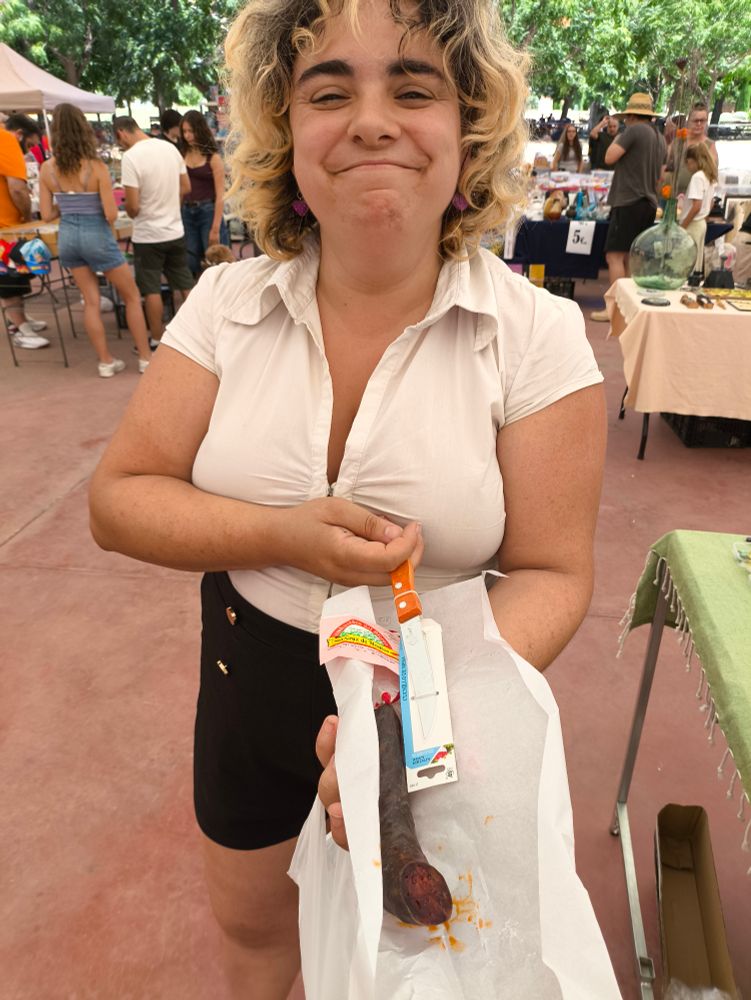 Mi mujer, posando muy sonriente con un chorizo y un cuchillo.