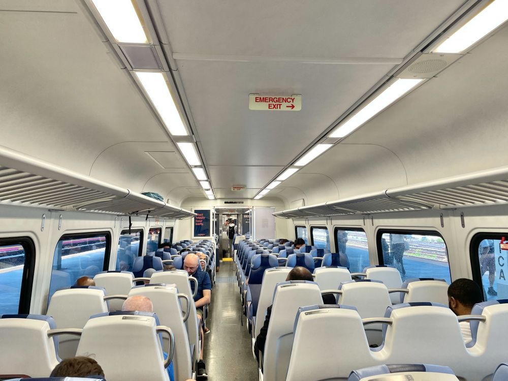 The interior of an LIRR M9 train with seated passengers. 