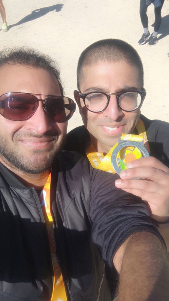 Two guys—one on the left wearing sunglasses (my brother), and me on the right squinting at the camera and holding my medal up. 