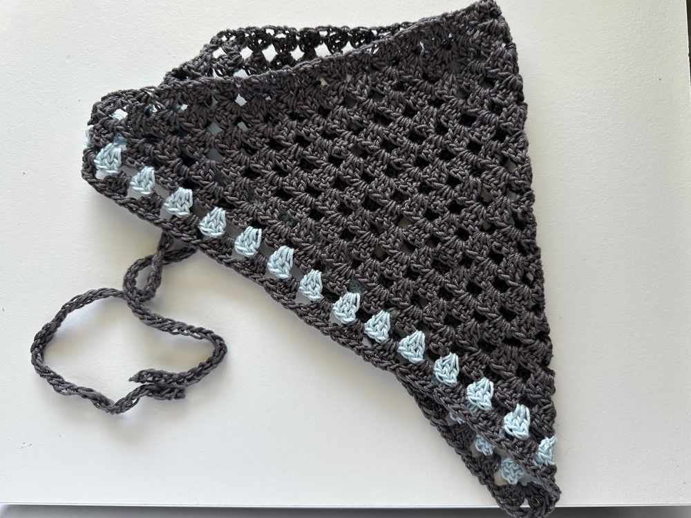 Crochet bandana made with granny stitches. The main color is brown, and there is one row of  baby blue. 