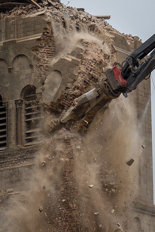 Demolition jaw of high-reach excavator destroying the NW tower of St Lambertus. 9 January 2018 10:11:20.51. Notice the wall core is stock brick rather than masonry rubble.

© Superbass / CC-BY-SA-4.0 (via Wikimedia Commons)