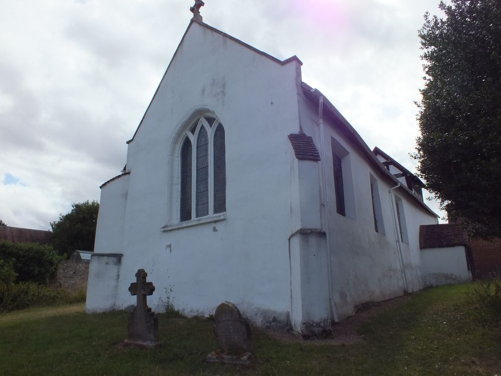 E end from NE. 3-light E window with no tracery, angle buttresses. The deep splays of the side windows suggest the chancel is old (13thc or earlier)