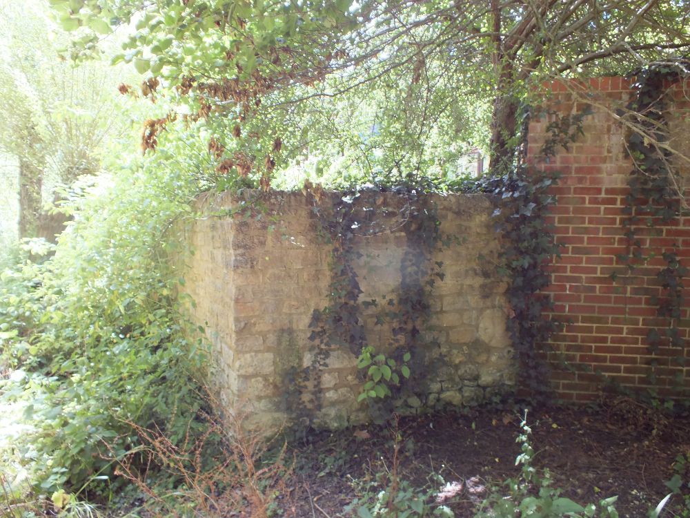 Angle of limestone wall, interfacing with modern brick.