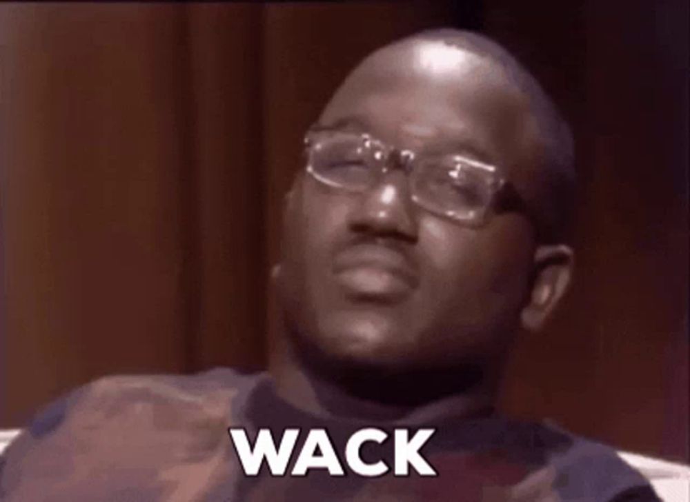 a man wearing glasses and a vest is sitting on a couch and says wack .