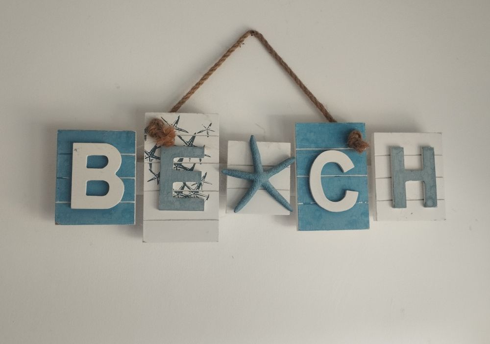 A bit of wall art in our holiday cottage showing a sign with wooden letters in white and blue spelling out "Beach" but the "A" has been replaced with a starfish which makes you read it more as a "T", so it looks like "Betch".