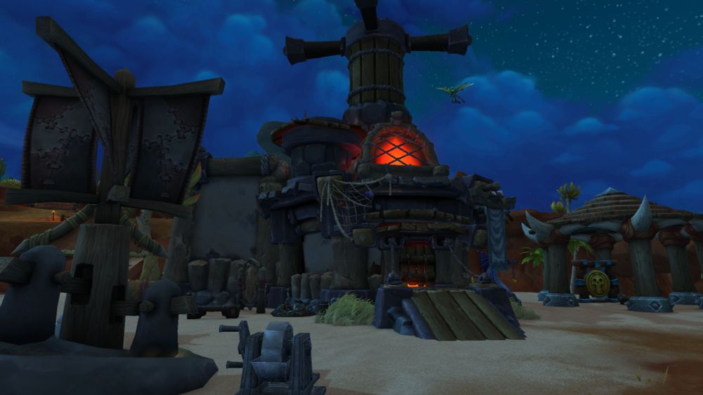 A nighttime scene from World of Warcraft showing an Orc-style blacksmith or forge building on a sandy coastline. The structure is bulky and rugged, made of dark stone, thick wooden beams, and metal plates. A large chimney rises from the center, wrapped with ropes, and glows an intense orange-red from the molten heat inside. The furnace opening at the front casts warm light onto the ground, with metal tools, an anvil, and piles of ore nearby. Tattered hide banners stitched together with leather cords hang from wooden posts on the left. To the right, a circular hut made of logs and massive animal bones stands near palm trees. The sky above is deep blue and filled with stars, with a single winged creature flying near the chimney.