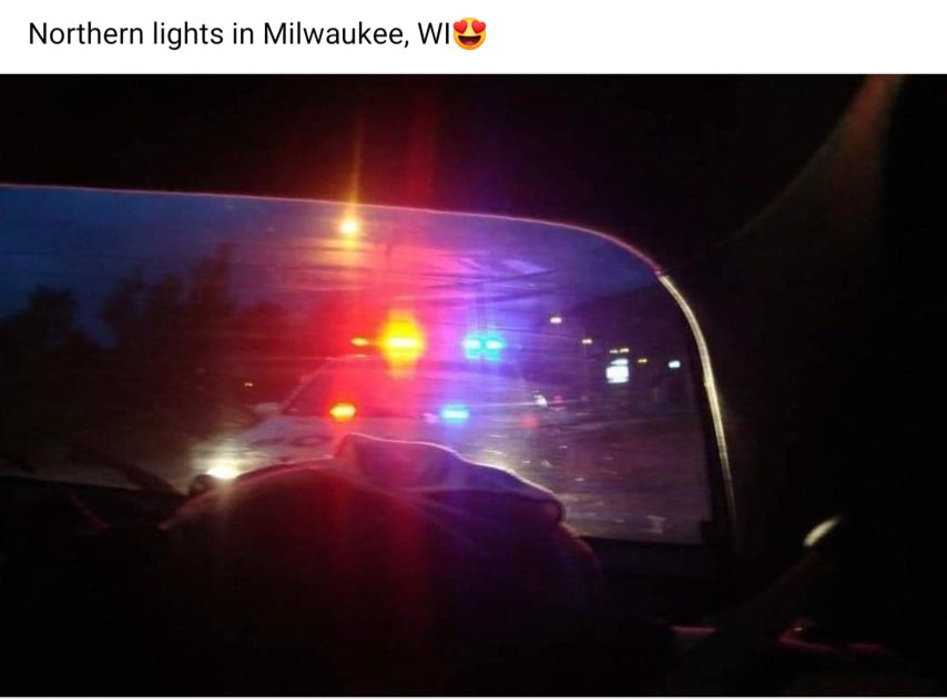 Northern lights in Milwaukee, WI (heart eyes emoji) Image: police car seen through the back window of a car, flashing the red and blues.