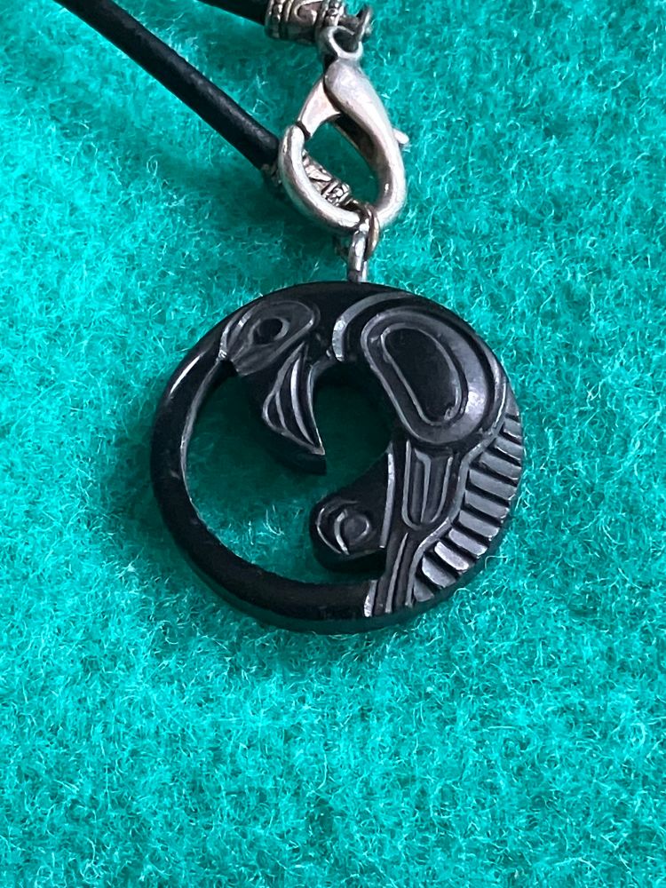 An argelite pendant of a Haida Raven. It was made by Haida artist Myles Edgars. Argelite is a black stone native to British Columbia’s west coast. 