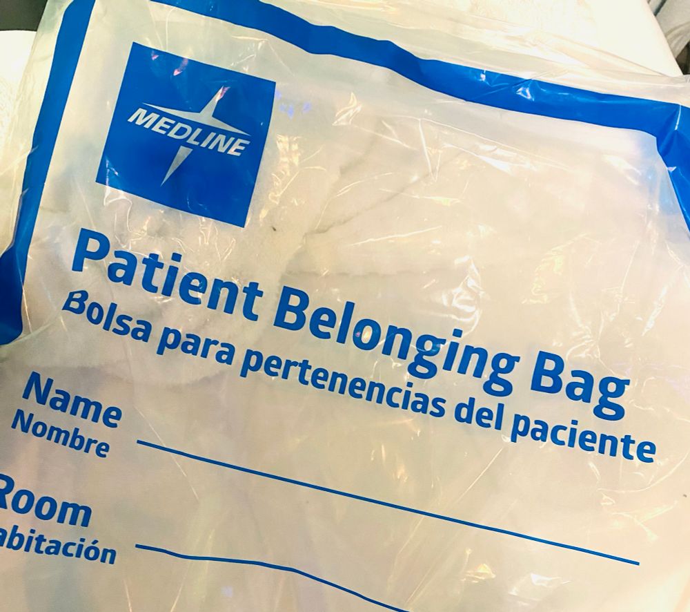 Flimsy plastic bag that is provided in hospitals for patients to store their personal things. “Patient Belonging Bag” is written in large blue letters across it.  