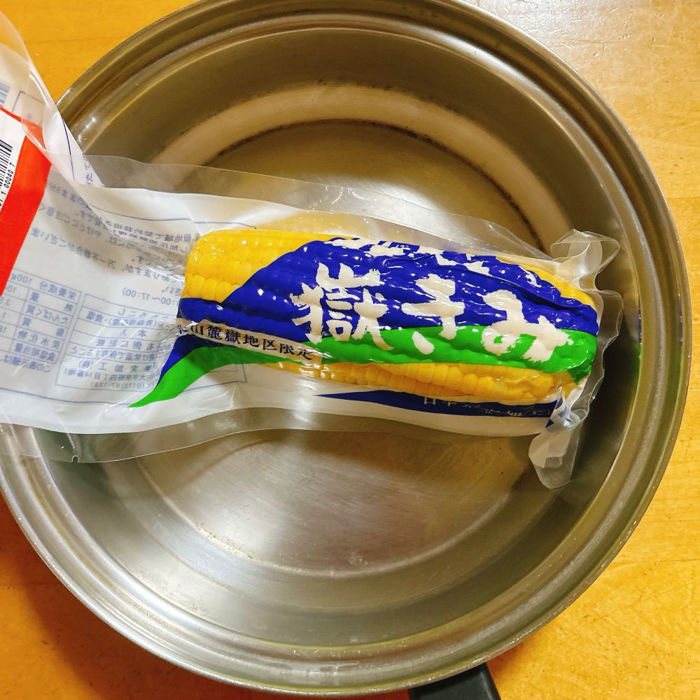 鍋に水を入れてレトルトコーンを入れたとこ。これからレトルトのまま加熱する。