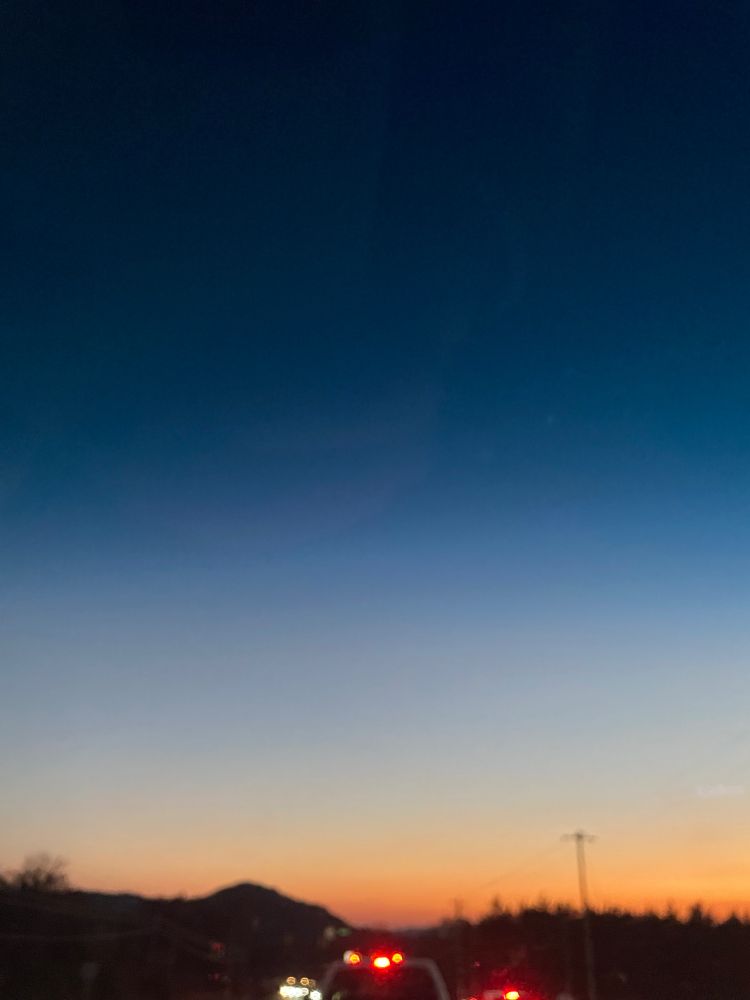 Sunset begins dark hills with red taillights in front 