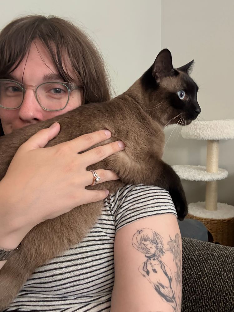 Jordan holding beep beep over her shoulder. Beep beep is a seal point short hair cat 