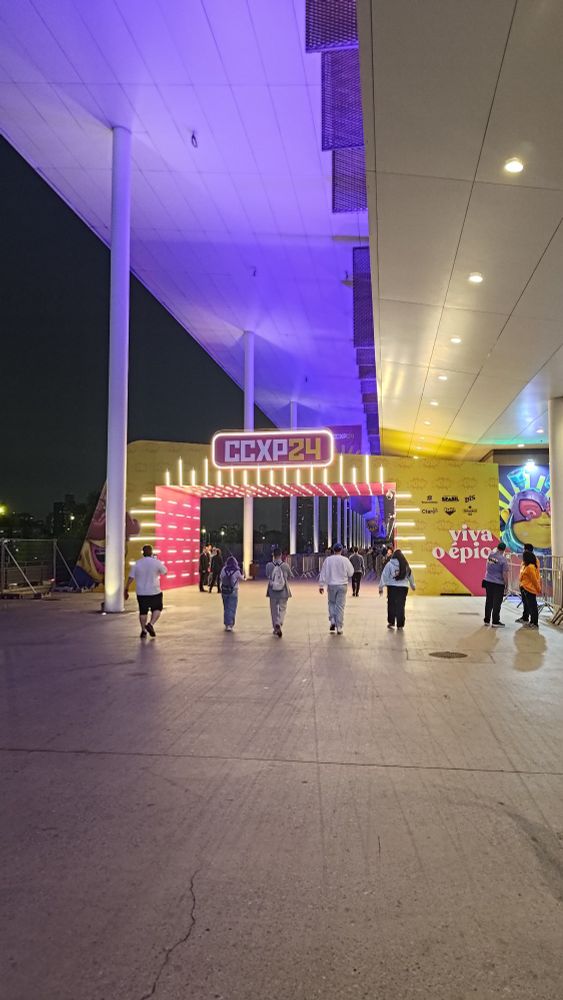 Entrada da ccxp, em amarelo e rosa, com um painel iluminado 