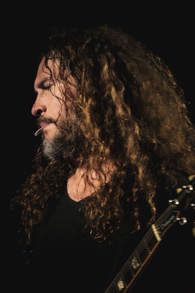 Side profile of Ray Toro with his guitar pick held between his lips. He is beautiful.