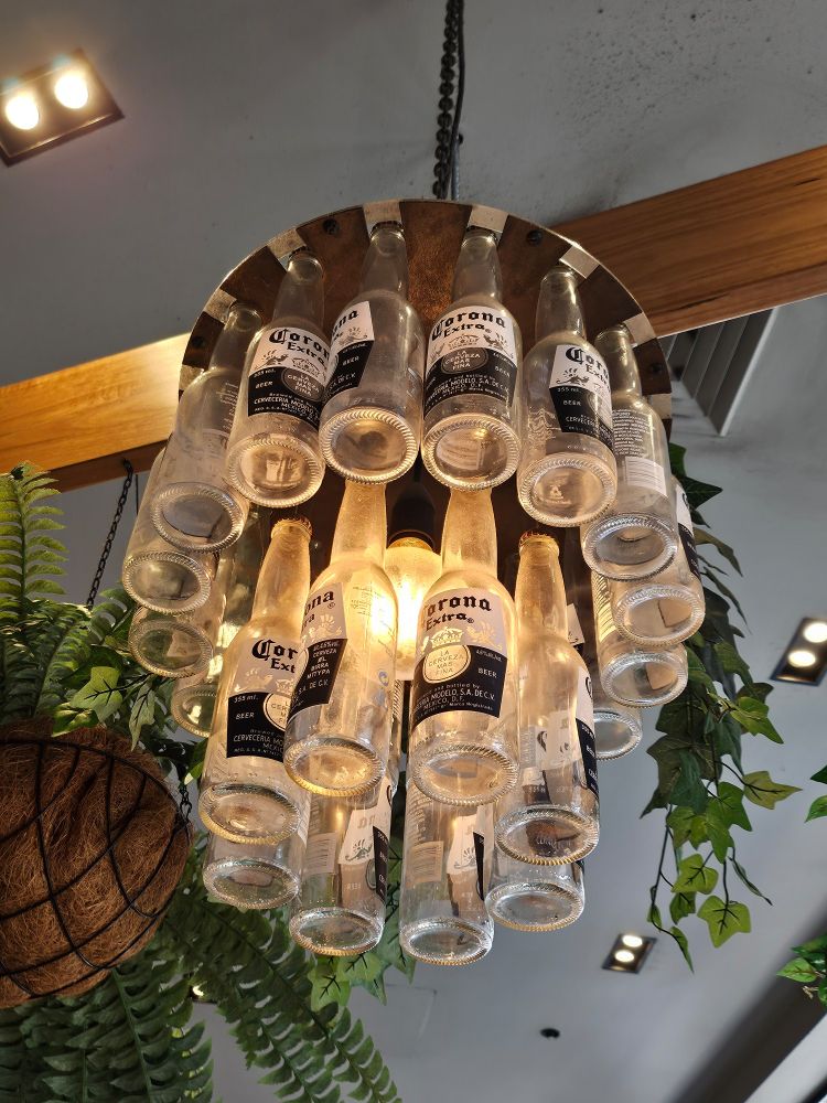 A light fitting made of empty bottles of Corona beer hangs from the ceiling, creating a chandelier effect. 