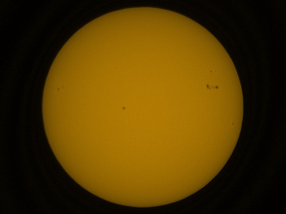 Image of the solar disk with sunspots visible. One sunspot near the center and a patch of sunspots near the limb at the right.