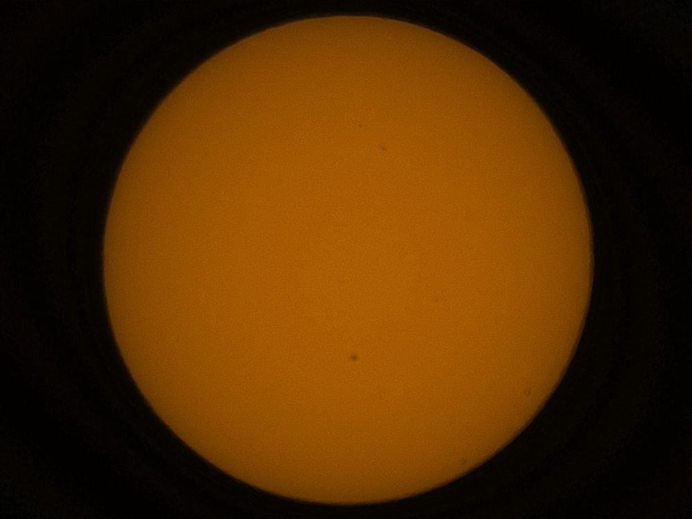 The solar disk imaged using a Unistellar EVScope with some small sunspots.