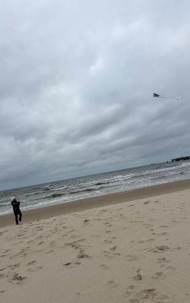 Kind am Strand mit Drachen, der bei Windstärke 5 an der Leine zieht