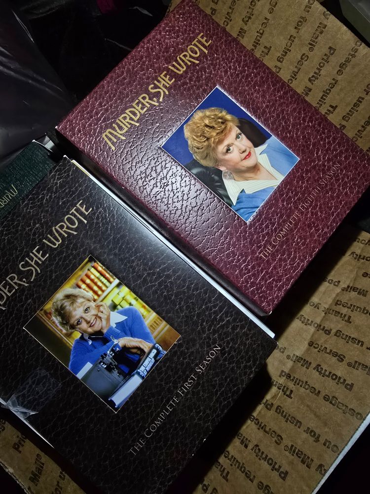 A box full of Murder, She Wrote dvds. The ones one top are The Complete First and Eigth Seasons