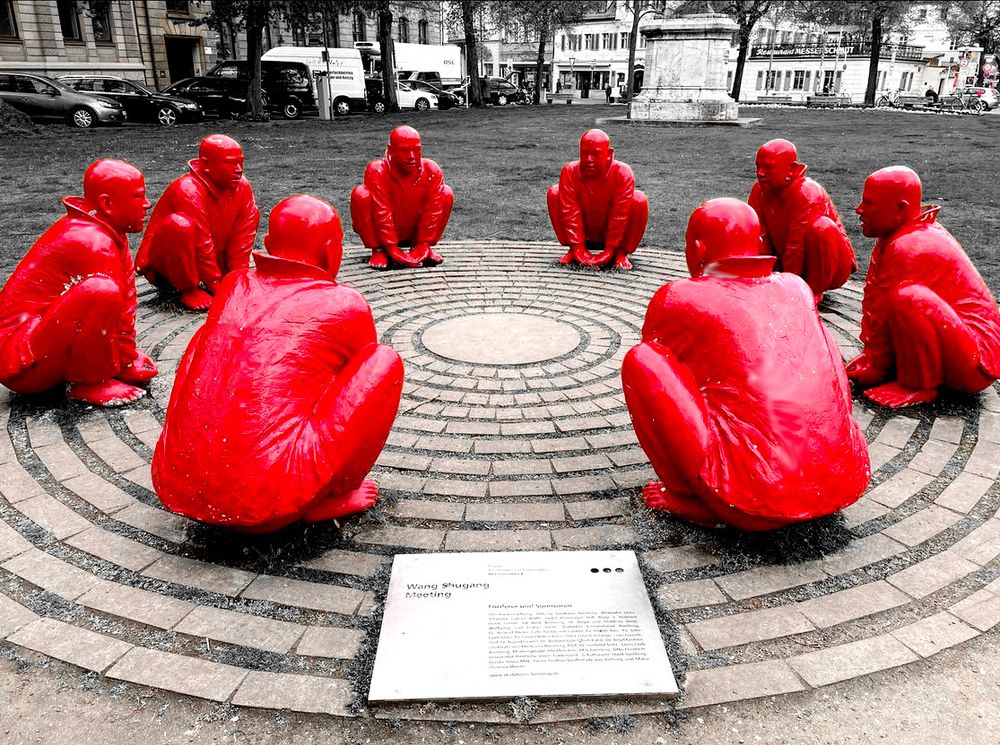 Das Meeting ist eine Installation des chinesischen Künstlers Wang Shugang. Sie besteht aus acht hockenden, lebensgroßen, roten Fiberglasmännern und wird im Volksmund oft als die „roten Männer“ bezeichnet.
Erstmals war dieses Kunstobjekt in Bamberg im Rahmen der Ausstellung CIRCLES – KREISE vom Juni bis August 2013 zu sehen. 
Im Okt. 2016 wurden die ursprünglichen Figuren aus Fiberglas durch identische Figuren aus Bronze ersetzt, die die Stadt Bamberg vom Künstler kaufte.