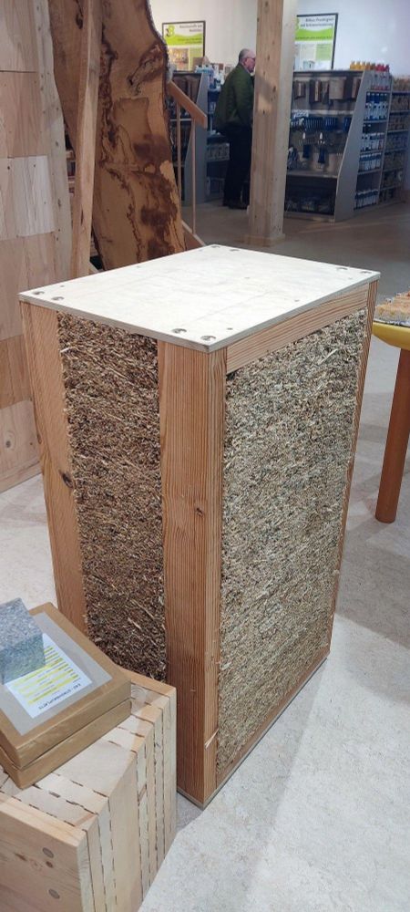 Straw panel, Holz 100, glue free, doweled masstimber wall section. Straw drywall boards with paper backing rest on top.