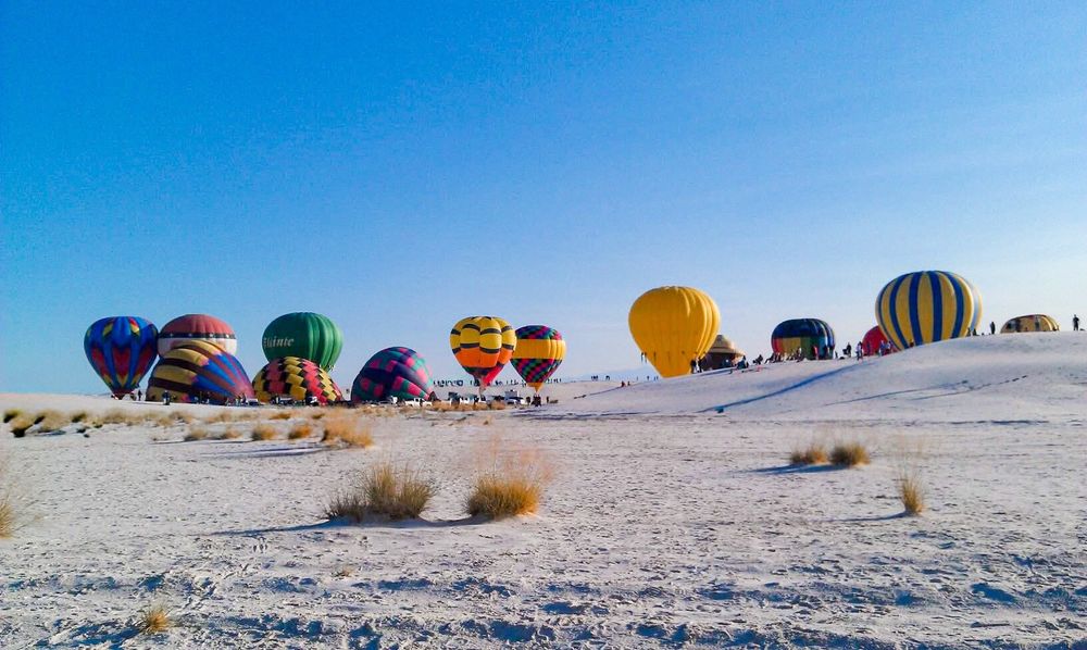 Hot air balloons inflating on white sand dunes at White Sands National Park. 