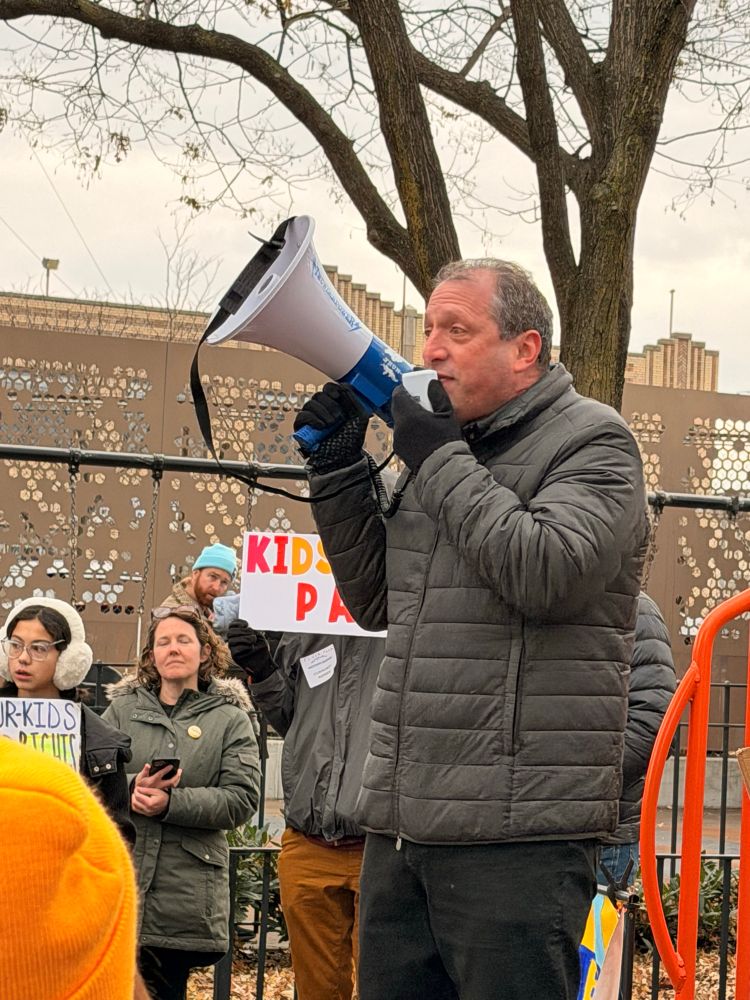 Brad Lander holding a megaphone surrounded by parents and children