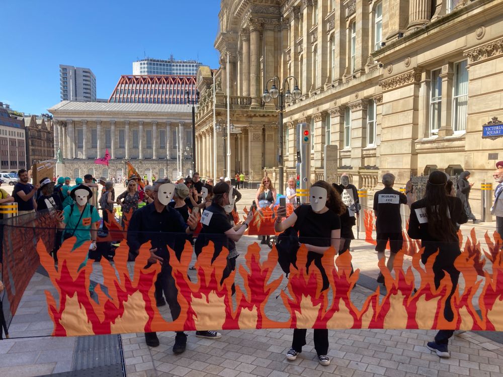 Burning Ballroom: A group of people dressed in black dress dance, each alone staring into a phone, while flames rise around them