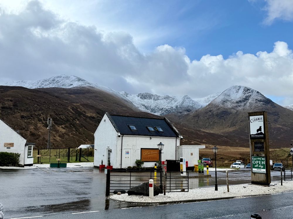 Snow covered mountains in the background and a small white old building in the foreground 