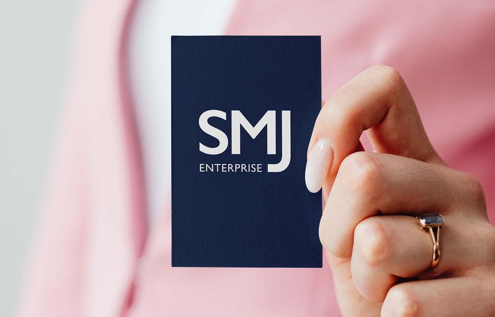 Woman in pink sweater holding business card.