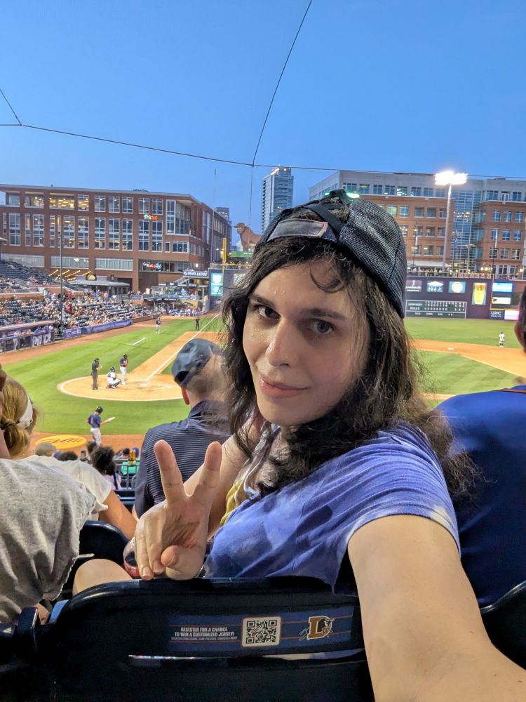 selfie at a Durham bulls game, the OP is making a peace sign and her hat is backwards because she is just THAT cool