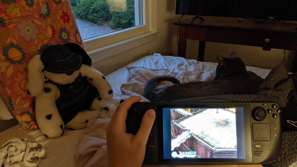 Steam deck playing ys origin in the foreground, cat and plush in the background