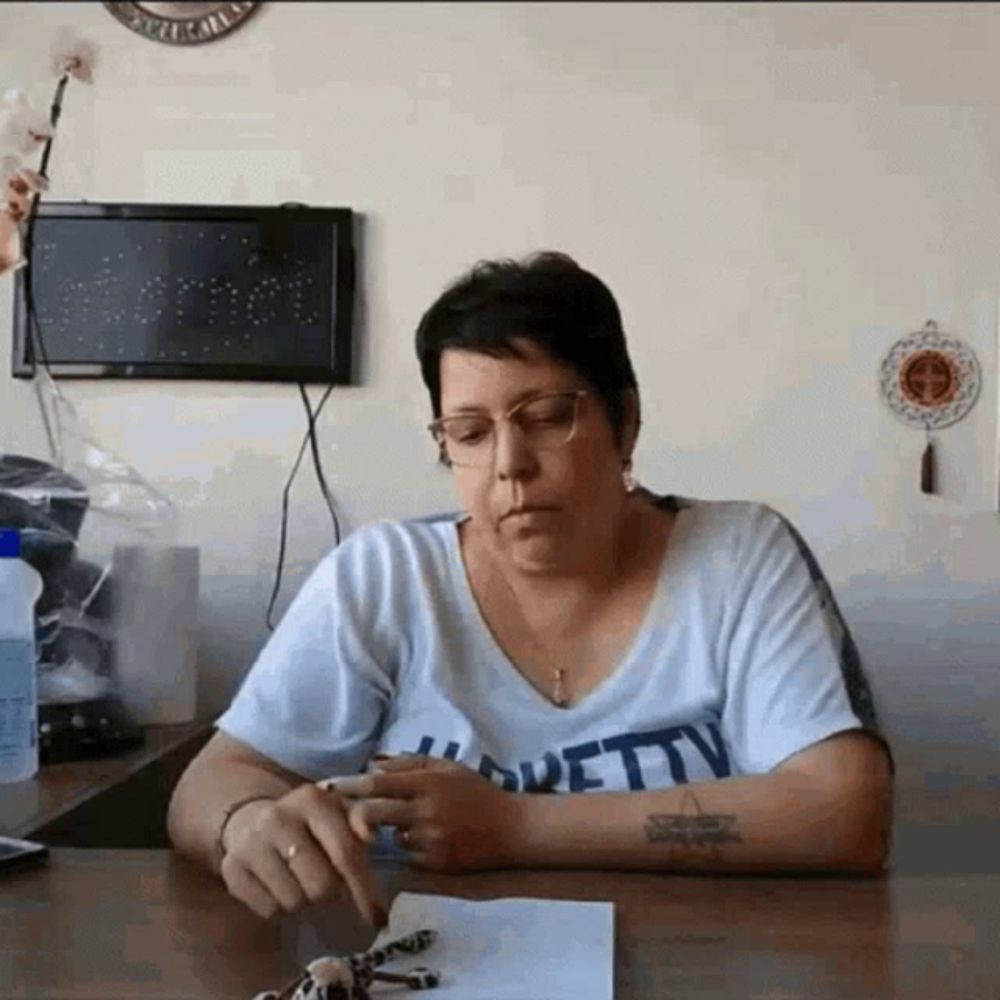 a woman wearing a shirt that says pretty sits at a table