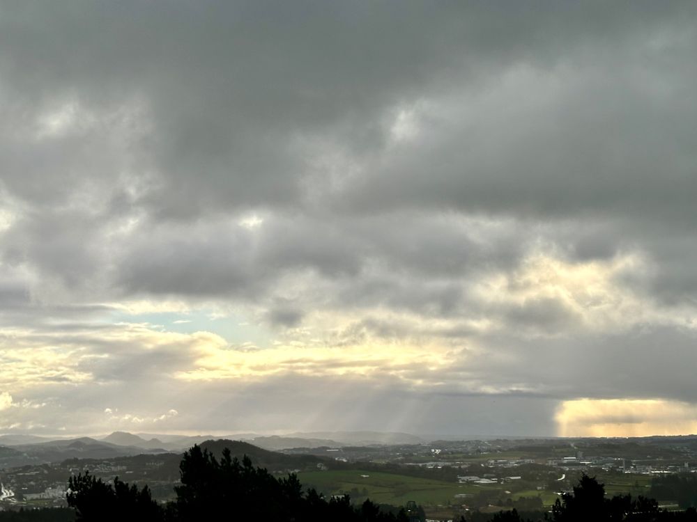 Cloudy landscape, sun rays coming through the clouds in the distance
