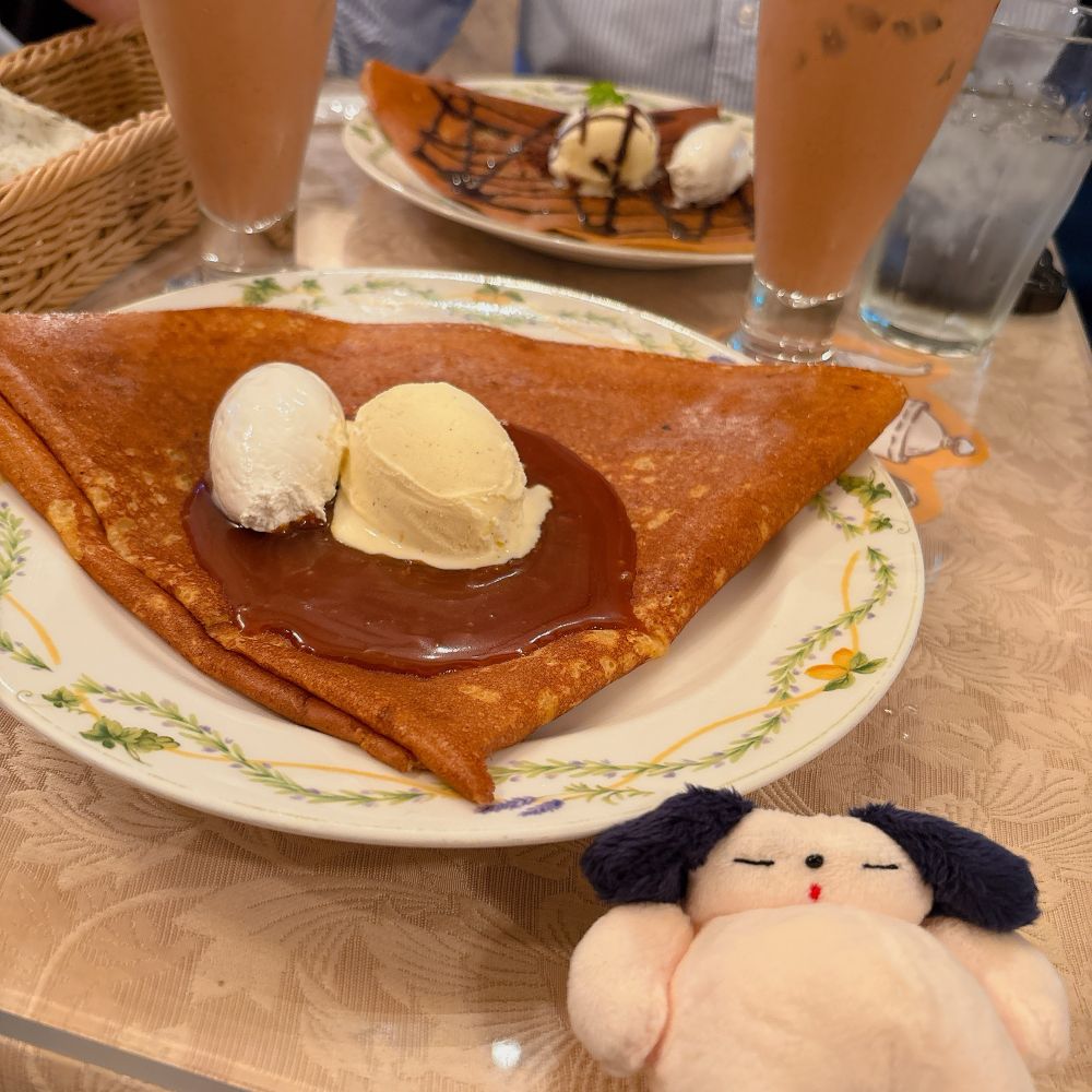 クレープリーアルションのクレープの写真。手前がミルクジャム、奥にショコラ。お腹がふっくらした犬のぬいぐるみ。