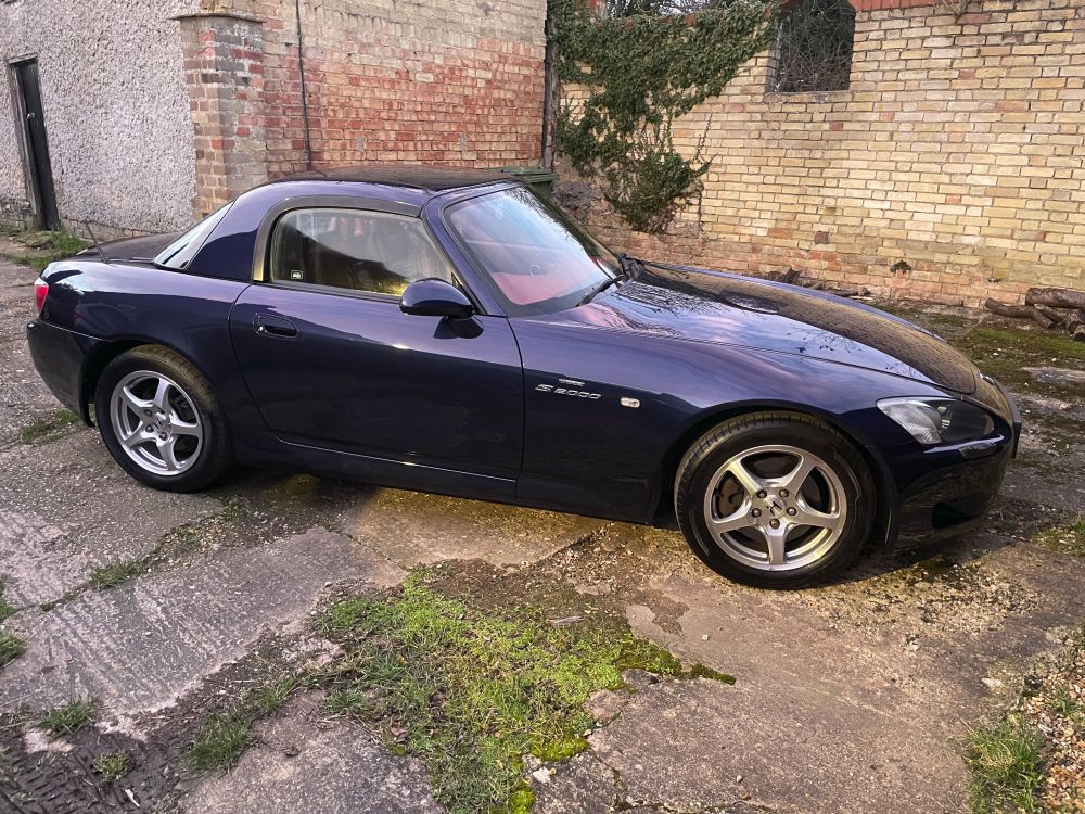 Dark blue Honda S2000 in front of an agricultural building.