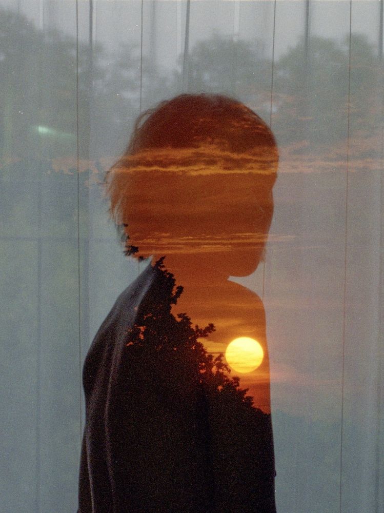 Analoge Doppelbelichtung. Eine Frau und die aufgehende Sonne.