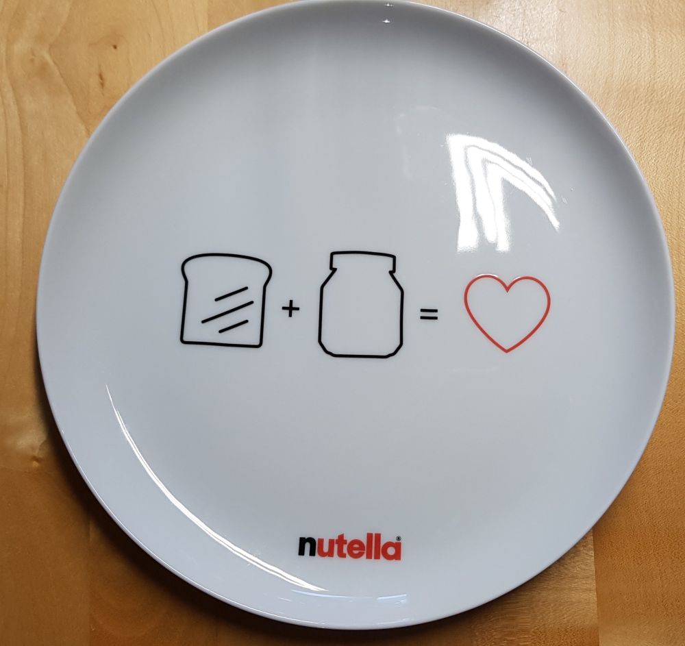 Teller von Nutella: auf dem Teller ist ein Toastbrot gezeichnet und ein Nutellaglas. Die Gleichung sagt Toastbrot + Nutellaglas = Herz