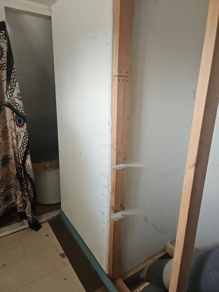 A photo of a non-load-bearing wall stud which is actually four separate pieces of wood screwed into drywall.