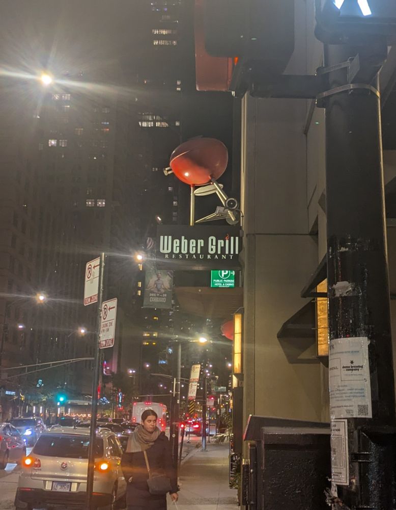 A Weber Grill Restaurant sign, with an oversized Weber grill, on a Chicago street at night 