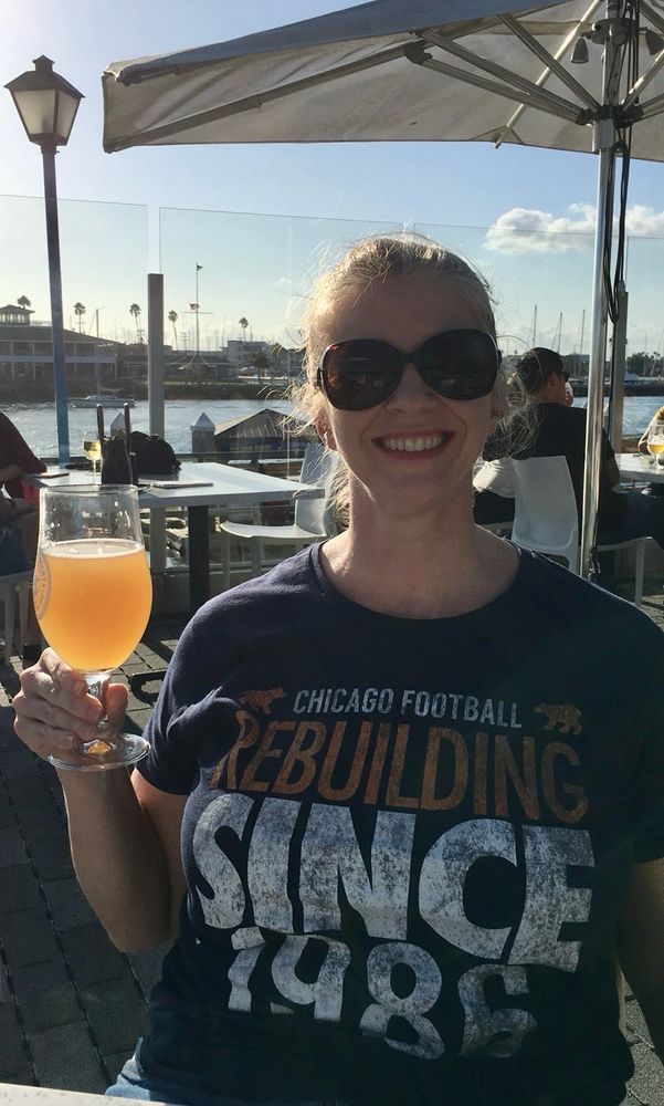 Women holding a beer wearing sunglasses and a shirt that says “Chicago Football Rebuilding Since 1986.”